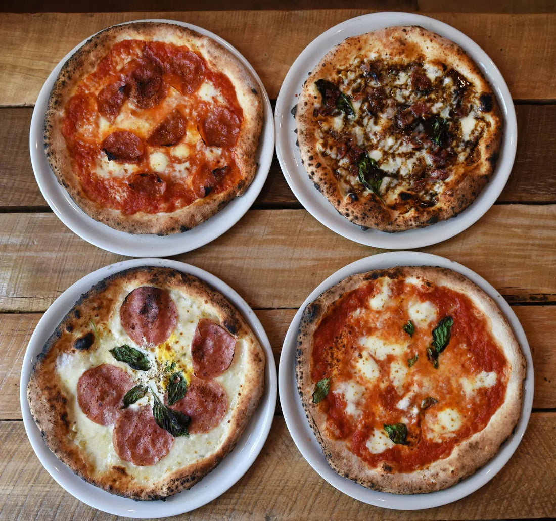 Four freshly baked pizzas on the plates