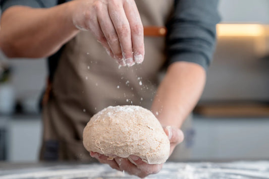 Person adding flour to dough