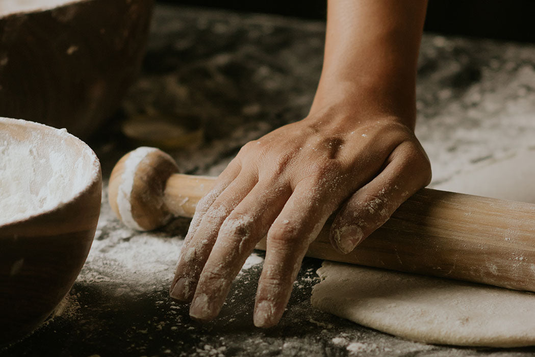 person working dough with rolling pin